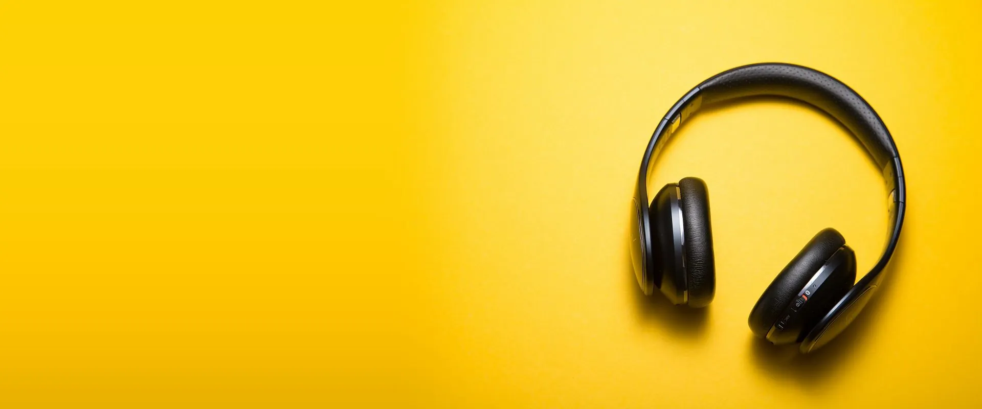 Black wireless headphones on a yellow background